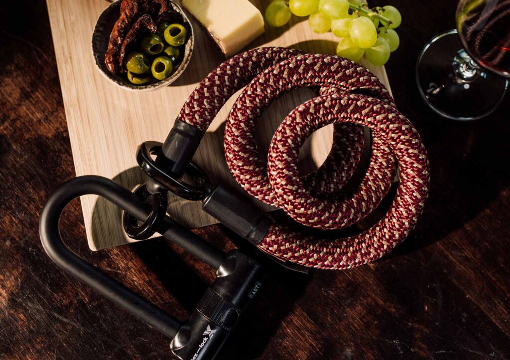 tex–lock eyelet in chateau red with X-lock lies wrapped together on a wooden board with antipasti and red wine