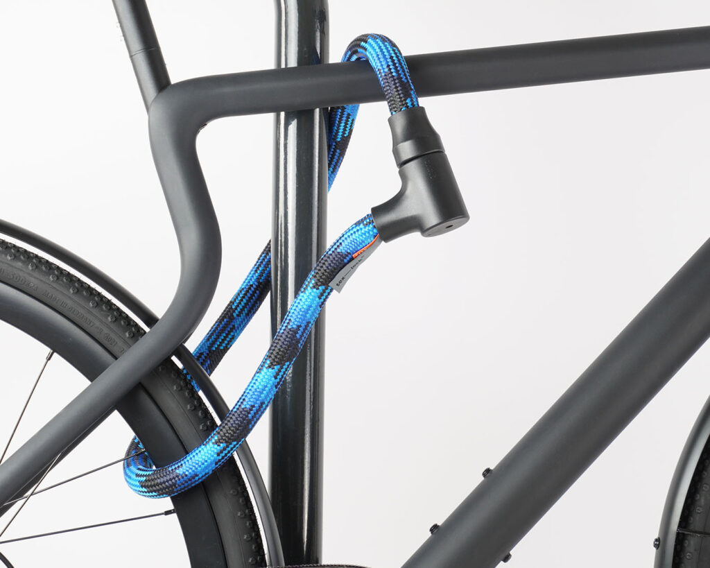 Bikes rear wheel and top tube connected to bike stand with blue and black textile rope lock