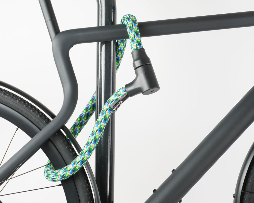Bikes rear wheel and top tube connected to bike stand with colourful textile rope lock