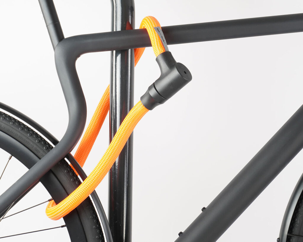 Bikes rear wheel and top tube connected to bike stand with orange textile rope lock